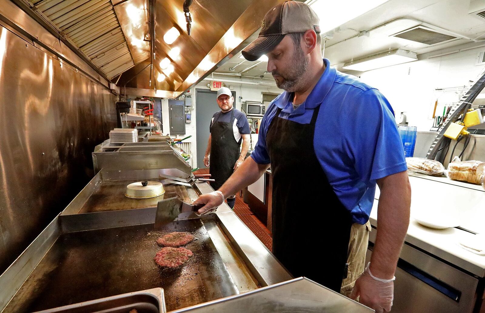Keith Hardwick, the owner of The Half Day Cafe, cooks a burger on the grill. BILL LACKEY/STAFF