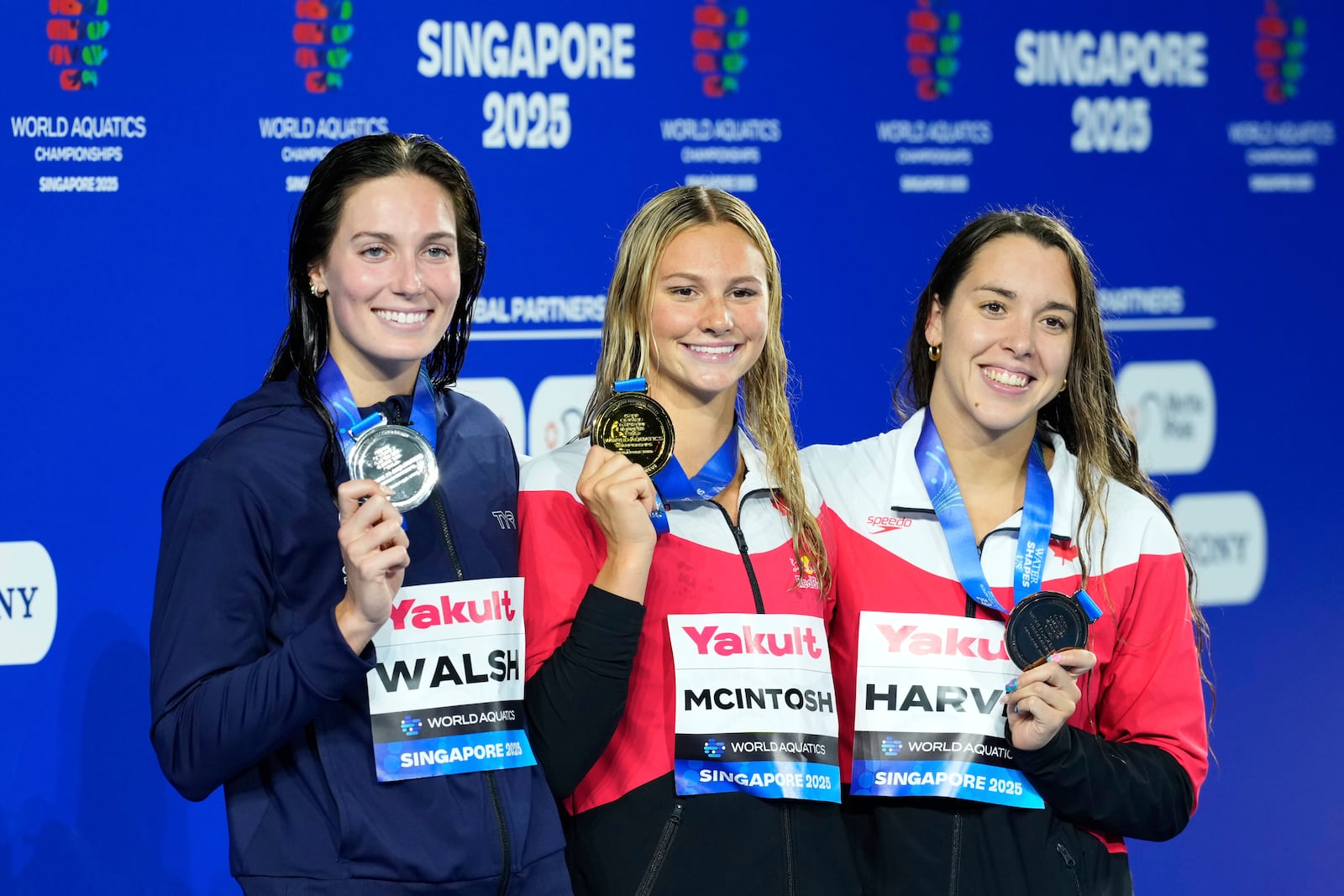 Gold medalist Summer McIntosh of Canada, center, flanked by silver medalist Alex Walsh of the United States, left, and bronze medalist Mary-Sophie Harvey of Canada pose on the podium after the women's 200-meter individual medley final at the World Aquatics Championships in Singapore, Monday, July 28, 2025. (AP Photo/Vincent Thian)