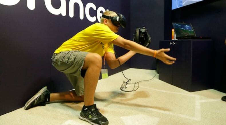 **HOLD FOR STORY BY RON BLUM FOR SUNDAY NIGHT JULY 9**Dennis Milman reaches to catch a virtual ball at the All Star FanFest, Friday, July 7, 2017, in Miami Beach, Fla. Fans put on goggles and a catcher mitt, crouch and get ready. They'll never catch a 104 mph from Aroldis Chapman. But at the All-Star FanFest they can feel like what it's like to be Buster Posey, receiving virtual pitches.(AP Photo/Alan Diaz)