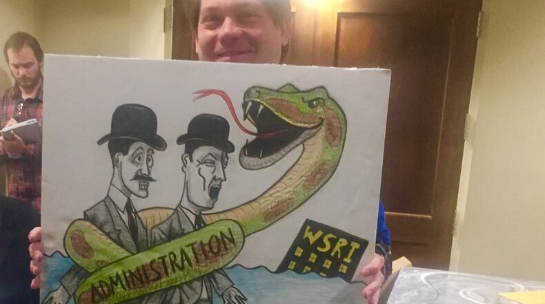 Wright State faculty members asked the university’s board of trustees to reinstate instructors who are set to be laid off. Some faculty stood at the back of the room to protest the cuts.