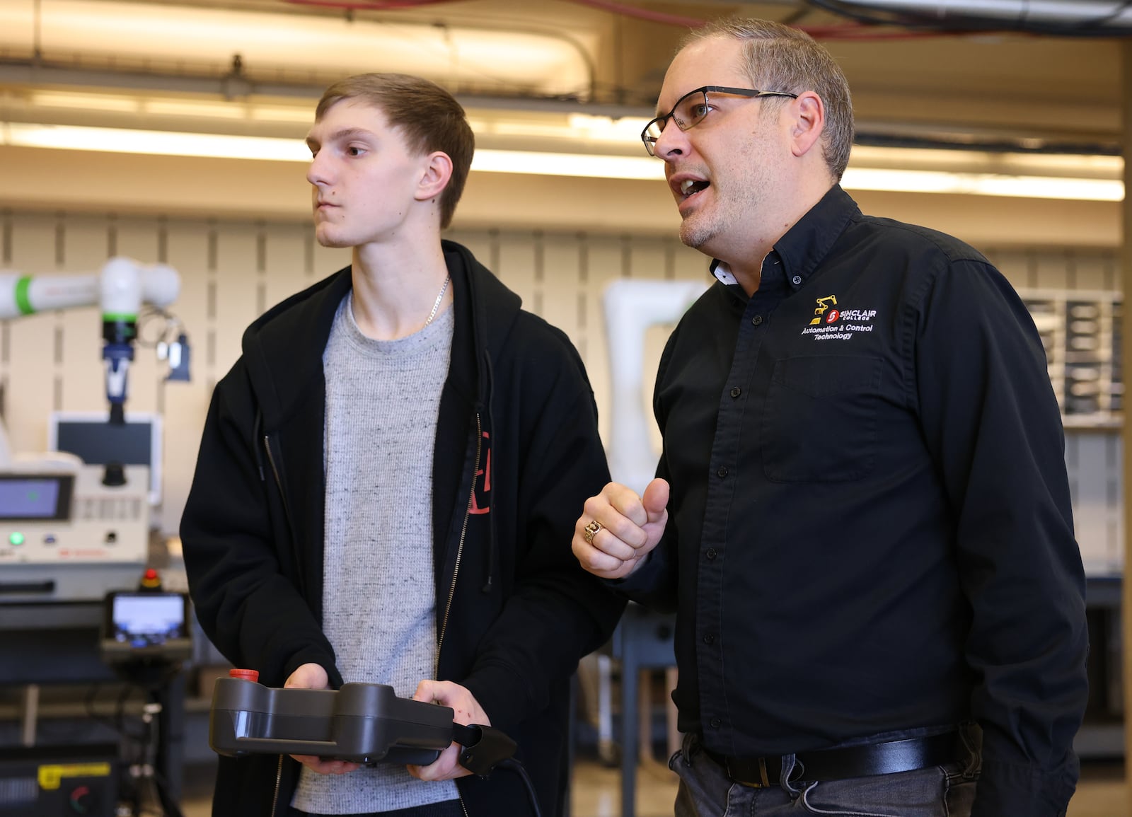 Adam Rain (right), program coordinator for electronics and robotics at Sinclair Community College, talks with student Travis Templeton in a lab on the campus on Monday, Nov. 24. BRYANT BILLING/STAFF