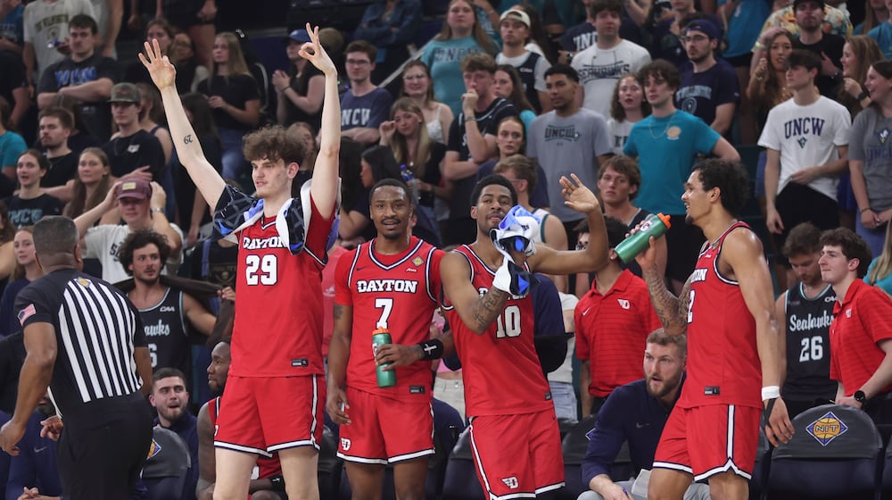 Dayton players react after a 3-pointer by Malcolm Thomas in the final minutes against North Carolina Wilmington in the first round of the National Invitation Tournament on Saturday, March 21, 2026, at Trask Coliseum in Wilmington, N.C.. David Jablonski/Staff