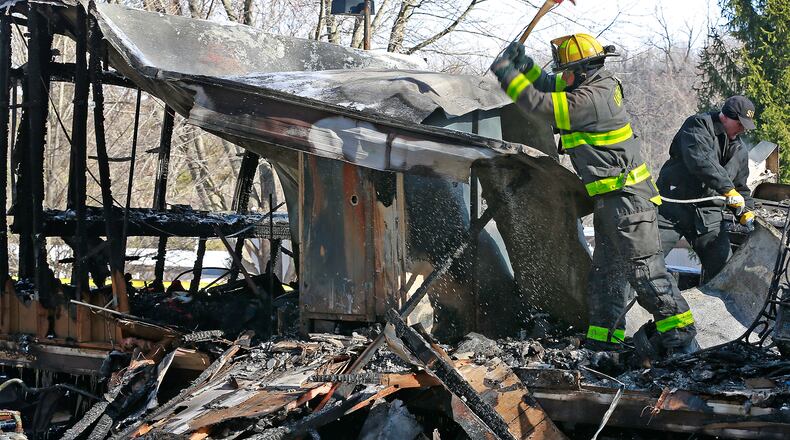 A firefighter from the Urbana Fire Division and the State Fire Marshall take apart the smoldering remains of a mobile home looking for a cause to last night’s fire that sent a family of four to the hospital. Bill Lackey/Staff
