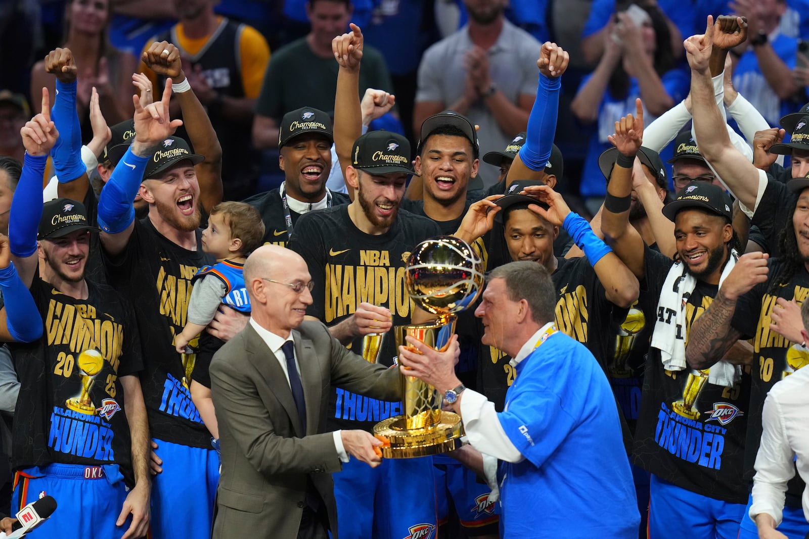 Clay Bennett, center right, chairman the ownership group of the Oklahoma City Thunder, receives the Larry O'Brien Championship Trophy from NBA Commissioner Adam Silver, center left, after winning the NBA basketball championship with a Game 7 victory against the Indiana Pacers Sunday, June 22, 2025, in Oklahoma City. (AP Photo/Nate Billings)