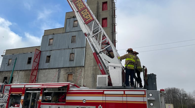 A participant is assisted by Dayton Fire Dept. personnel as she ascends the 137-foot aerial ladder during Saturday's Fire Camp for Women event. AIMEE HANCOCK/STAFF