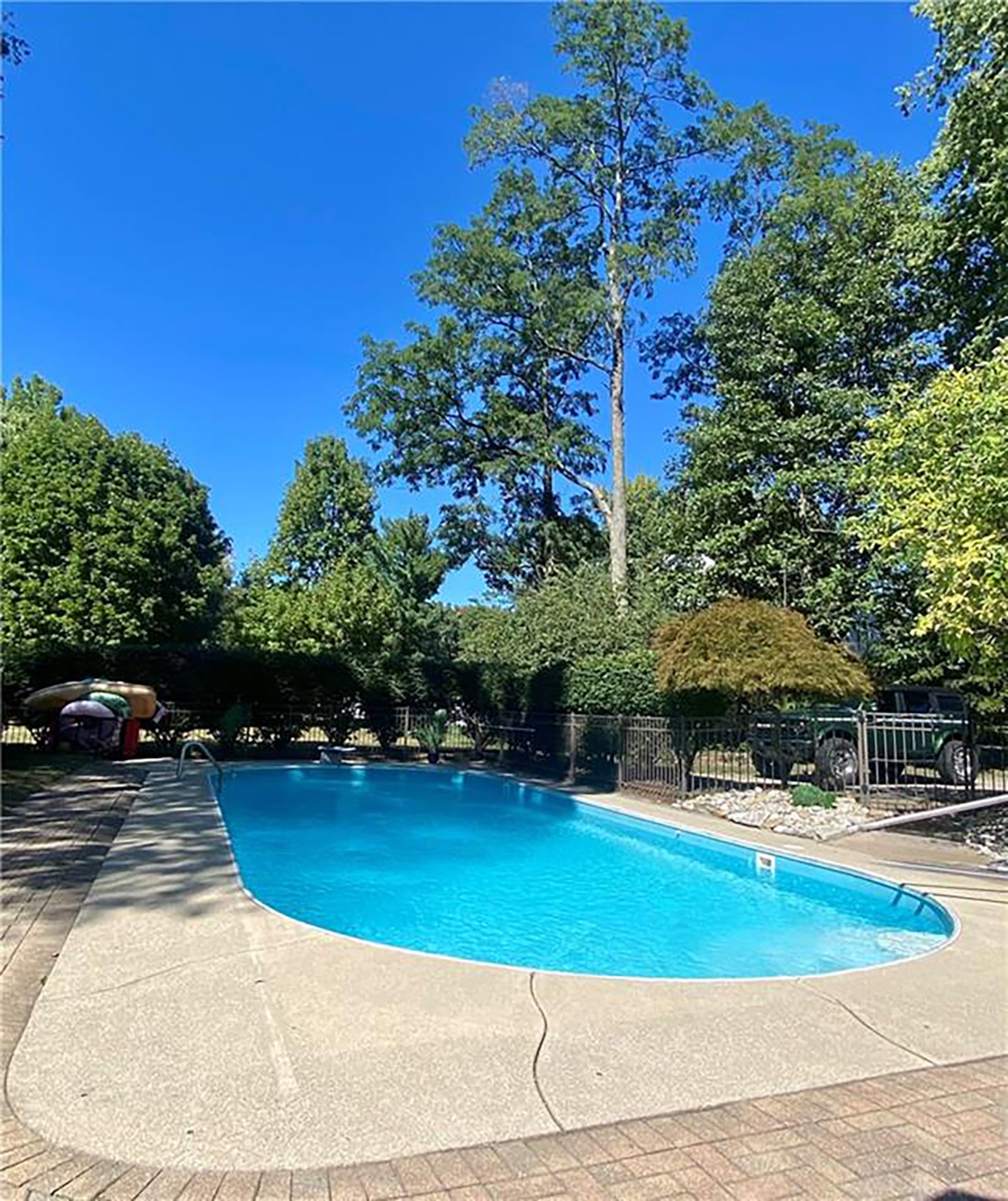 The inground pool has a diving board and is surrounded by concrete and pavers. CONTRIBUTED