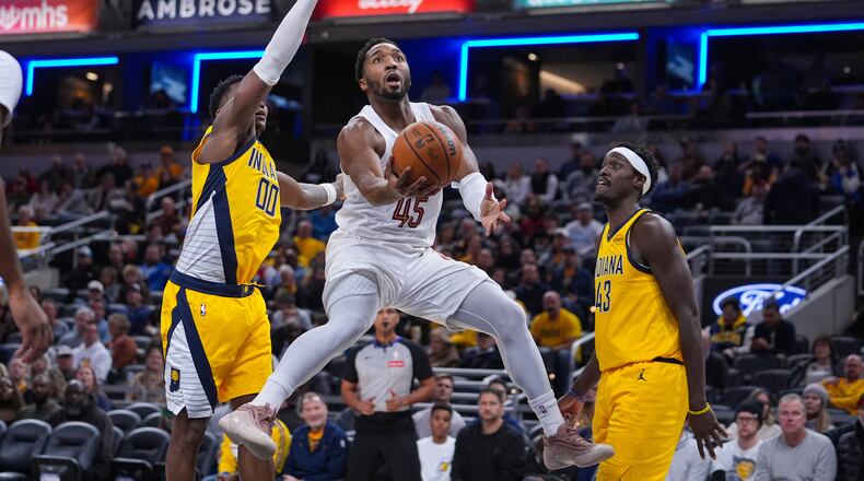 Cleveland Cavaliers guard Donovan Mitchell (45) shoots between Indiana Pacers guard Bennedict Mathurin (00) and forward Pascal Siakam (43) during the first half of an NBA basketball game in Indianapolis, Monday, Dec. 1, 2025. (AP Photo/Michael Conroy)