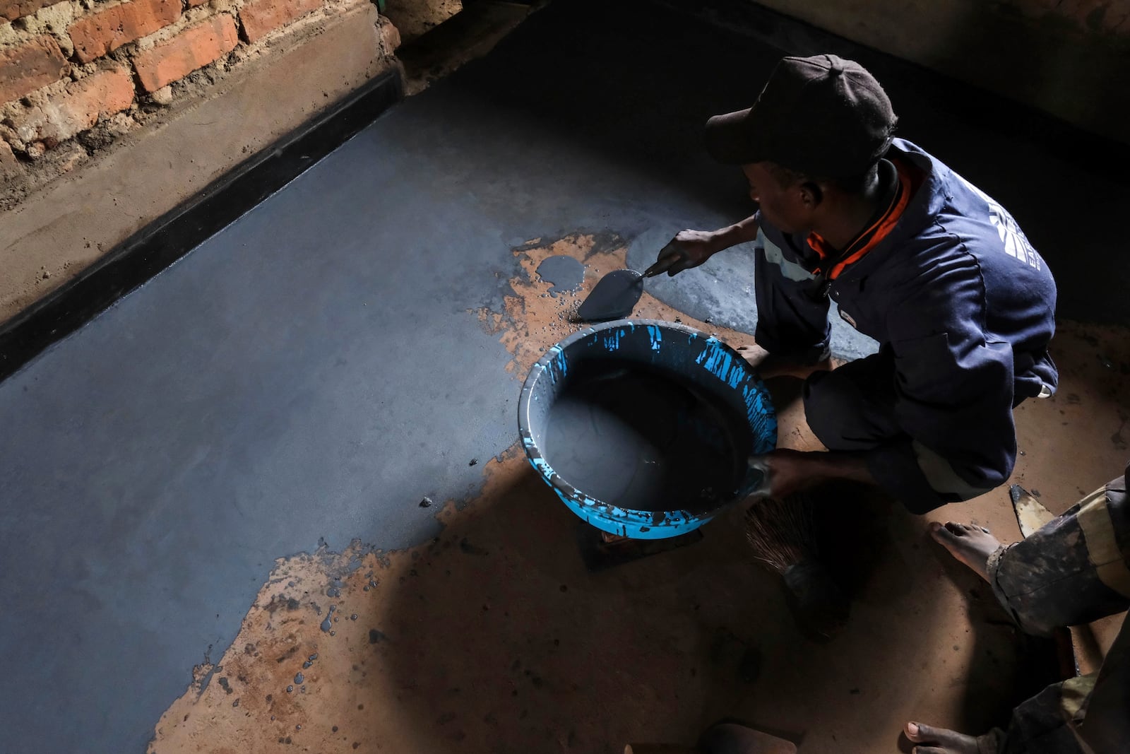 Alex Wanda, a construction officer at EarthEnable, installs paste on floors May 17, 2025, in Jinja, Uganda. (AP Photo/Hajarah Nalwadda)