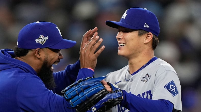 Los Angeles Dodgers pitcher Yoshinobu Yamamoto celebrates with right fielder Teoscar Hernández after throwing compete game against the Toronto Blue Jays in Game 2 of baseball's World Series, Saturday, Oct. 25, 2025, in Toronto. (AP Photo/Brynn Anderson)