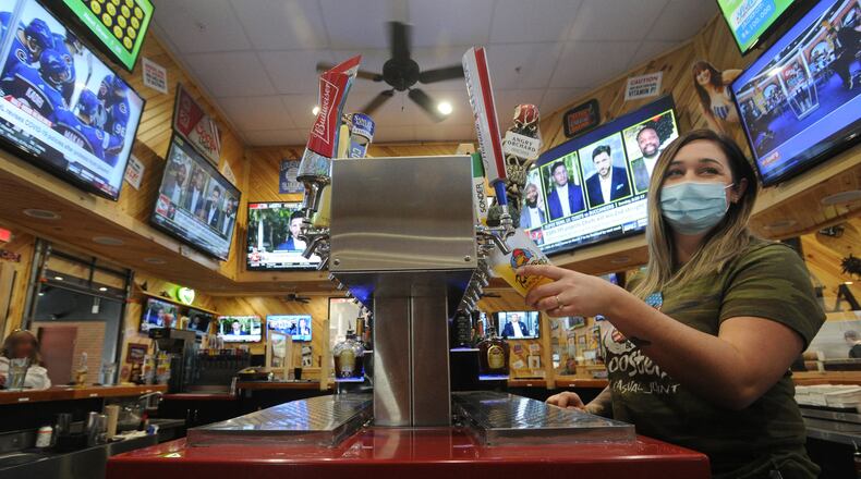 Breanna Dennis, the bartender at Roosters on Springboro Pike pours a beer for a customer, Friday, Feb. 5, 2021. The restaurant is working to keep customers and staff safe on Super Bowl Sunday. One of their busiest days of the year. MARSHALL GORBY\STAFF