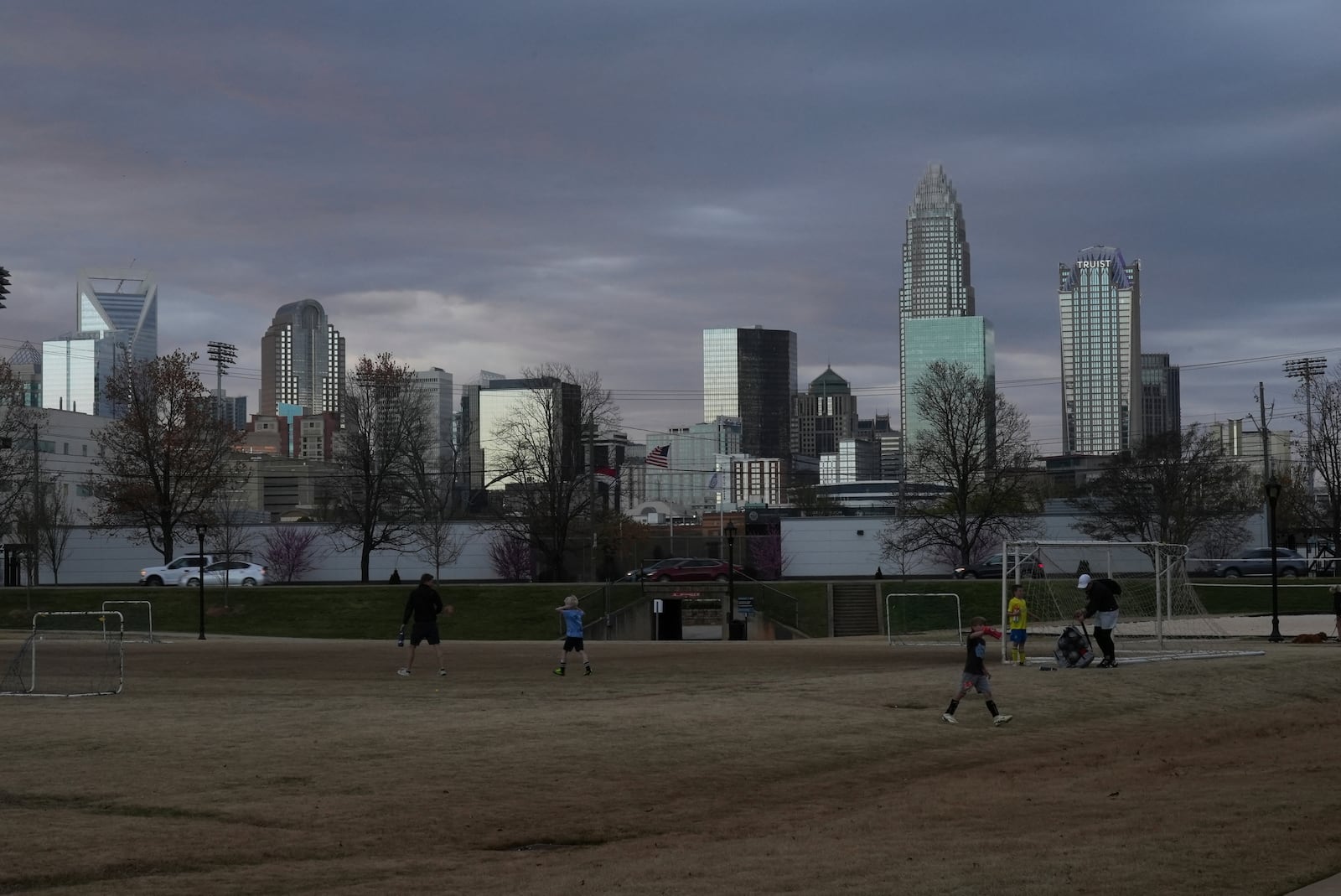 Children walk through a sports field in Independence Park under the skyline of Charlotte, N.C., on March 20, 2025. (AP Photo/Mary Conlon)