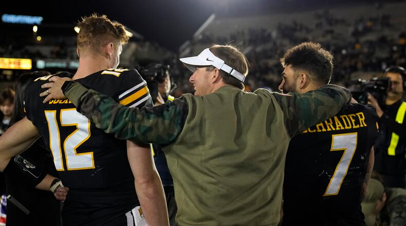 Missouri head coach Eliah Drinkwitz, center, hugs Missouri quarterback Brady Cook (12) and running back Cody Schrader (7) following an NCAA college football game against Tennessee Saturday, Nov. 11, 2023, in Columbia, Mo. Missouri won 36-7. (AP Photo/Jeff Roberson)
