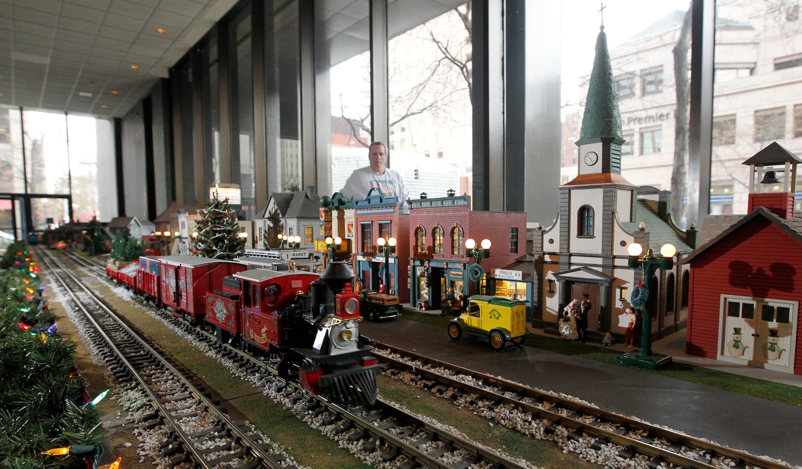 The Christmas train, loaded with evergreens, is one of three trains on the tracks of the Virginia Kettering holiday train display in the Kettering Tower lobby.  LISA POWELL / STAFF