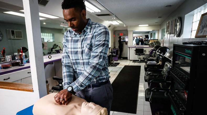 City Stars Unlimited Barber and Salon owner, Jonathan Cain demonstrates how to perform CPR and use a defibrillator at his business Tuesday morning March 5, 2022. Cain partners with Premier Health's Barbershop Health Program to improve health for his customers and his community. Cain and other barbers recently received defibrillators for their shops and training in first aid. JIM NOELKER/STAFF