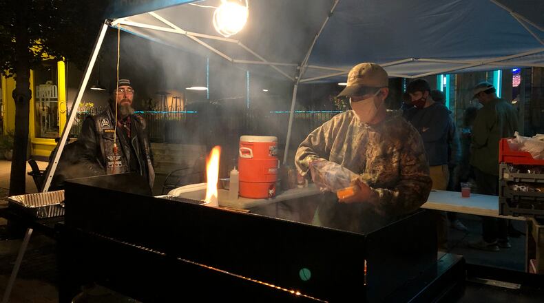A street vendor in the Oregon District makes hamburgers for customers earlier this month. CORNELIUS FROLIK / STAFF