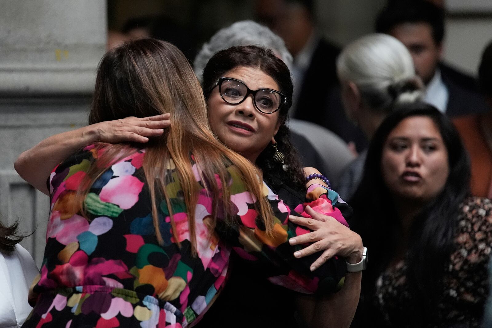 A staff member offers condolences to Mexico City Mayor Clara Brugada, facing camera, at a press conference where she spoke about the assassination of her personal secretary and one of her advisors who were killed earlier in the day by gunmen on a motorcycle, in Mexico City, Tuesday, May 20, 2025. (AP Photo/Marco Ugarte)