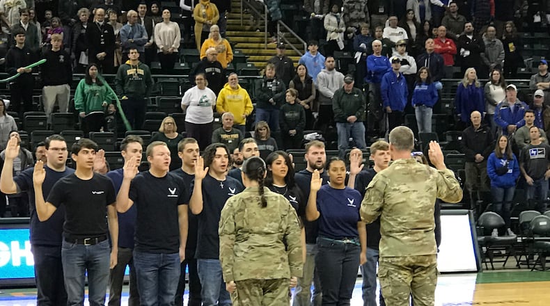 During halftime of the Stars, Stripes & Flight Classic featuring Wright State and Air Force, a dozen U.S. Air Force recruits, including three former Miami Valley high school athletes – Akiaya Rhinehart (front row of recruits, far right) the Fairborn High wrestling standout who was the state runner up at heavyweight with a 42-2 record last year; Trevor Parthemore, (behind Rhinehart) a four-year football starter at Urbana High who was the team captain; and Madison Taylor (next to Rhinehart) a Wayne High basketball and volleyball player – stood at midcourt in the Nutter Center and took the oath of enlistment as they were sworn in by  Wright Patterson AFB brass Col. Dustin Richards, 88th Air Base Wing and installation commander, and Chief Master Sgt. Tessa Fontaine. Tom Archdeacon/CONTRIBUTED