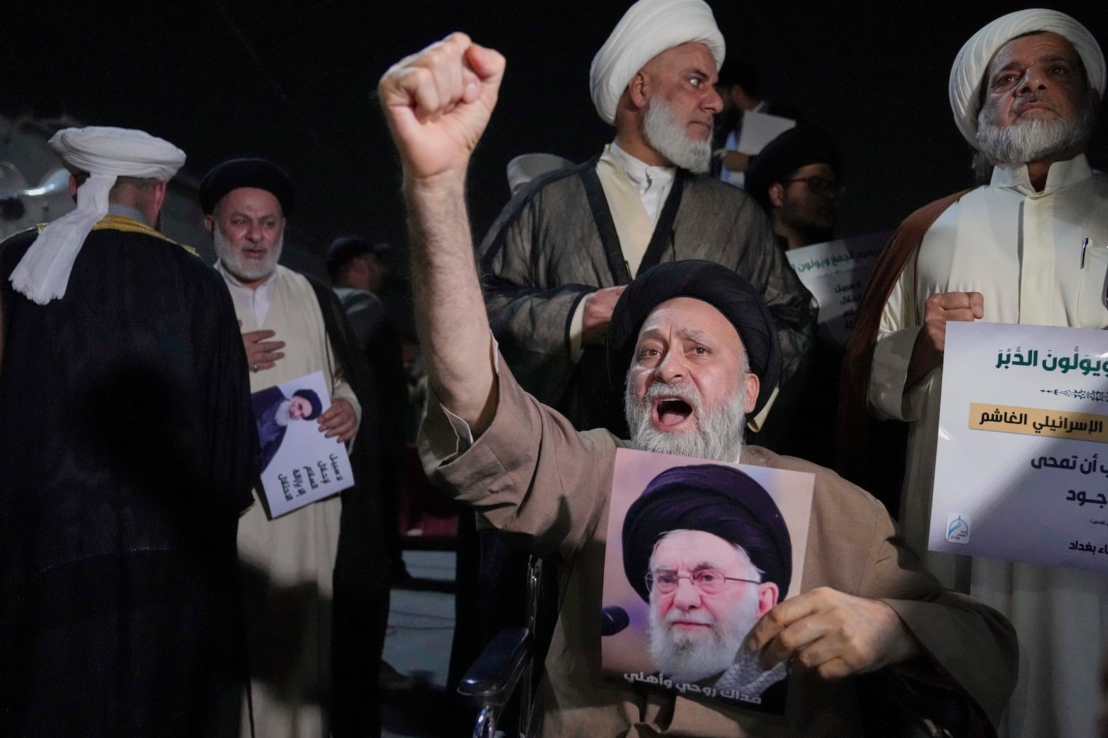 An Iraqi Shiite cleric holds a portrait of Iran's Supreme Leader Ayatollah Ali Khamenei during a protest against Israeli attacks on multiple cities across Iran, at a bridge leading to the fortified Green Zone where the U.S. Embassy is located in Baghdad, Iraq, Thursday, June 19, 2025. (AP Photo/Hadi Mizban)