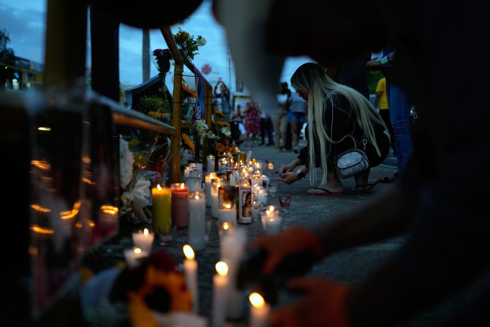A woman lights a candle at a makeshift memorial outside the Jet Set nightclub, in memory of the more than 200 people who died when its roof collapsed, in Santo Domingo, Dominican Republic, Friday, April 11, 2025. (AP Photo/Matias Delacroix)