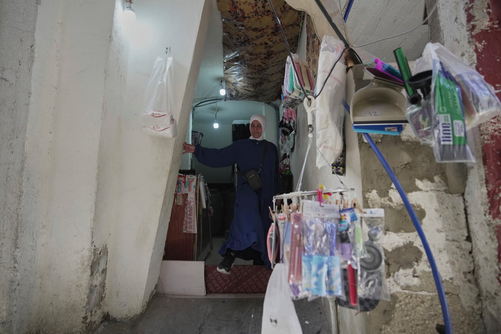 Ibtisam Salem, a 51-year-old Palestinian refugee and single mother, stands at the entrance of her home in the Mar Elias refugee camp in Beirut, Lebanon, Monday, June 2, 2025. She lives in a one-bedroom apartment shared with extended family members. (AP Photo/Hassan Ammar)