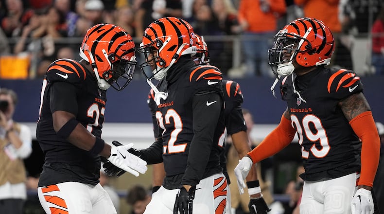 Cincinnati Bengals safety Geno Stone (22), center, celebrates an interception with safety Jordan Battle (27) and cornerback Cam Taylor-Britt (29) during the first half of an NFL football game against the Dallas Cowboys, Monday, Dec. 9, 2024, in Arlington, Texas. (AP Photo/Tony Gutierrez)
