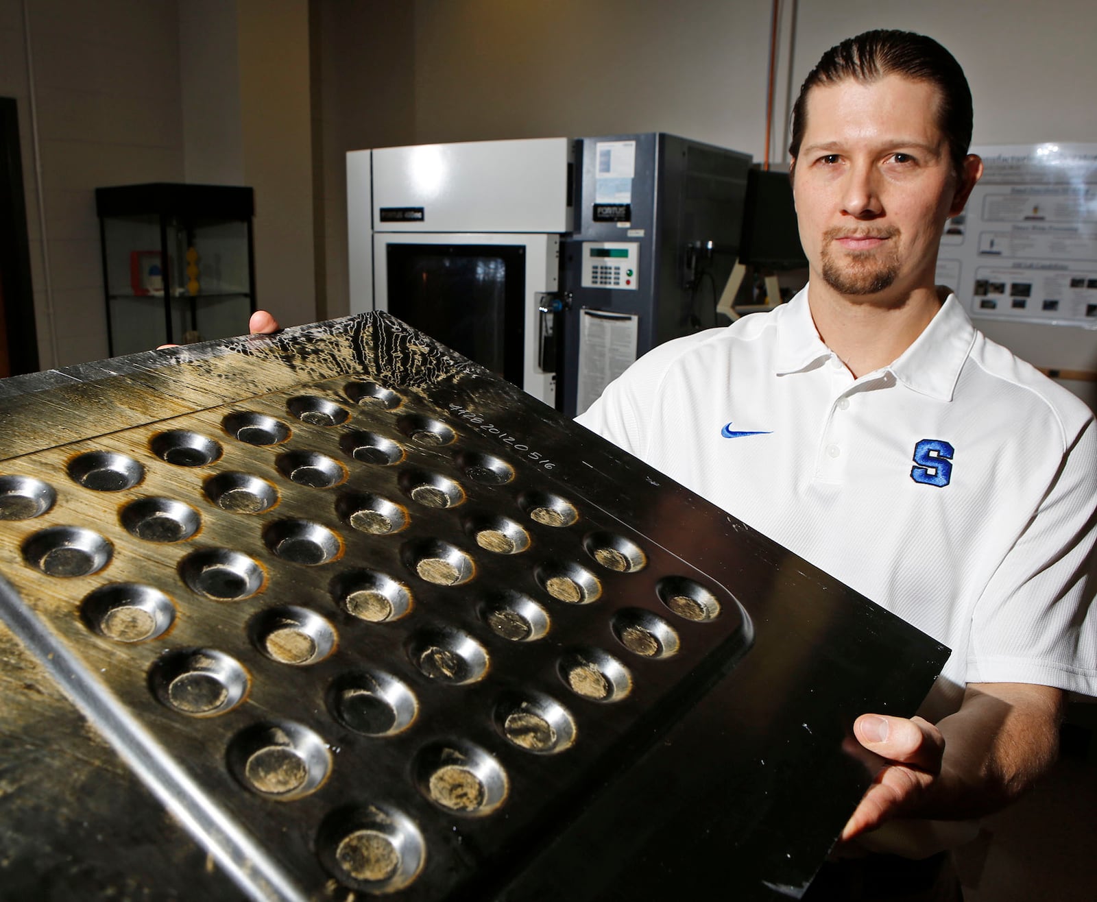Fastlane is a University of Dayton-based program to help regional manufacturers. In this 2015 photo, UD Research Institute Composites Manufacturing & Testing Group Leader T. Jared Stonecash displays a continuous carbon fiber and epoxy proof of concept part made with a compression mold. FILE