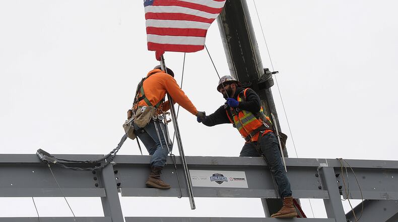 Workers shake hands Thursday April 6, 2023 after placing the final beam on the new press box at Welcome Statium. MARSHALL GORBY\STAFF