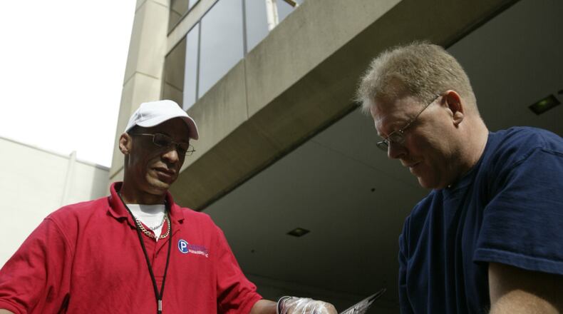 City Garage maintenance employee Kevin Price and the owner of the Coffee Chamber Jeff Morris inspect a dead falcon at 130 W Second St./ 1st National Plaza in downtown in this 2001 photo.