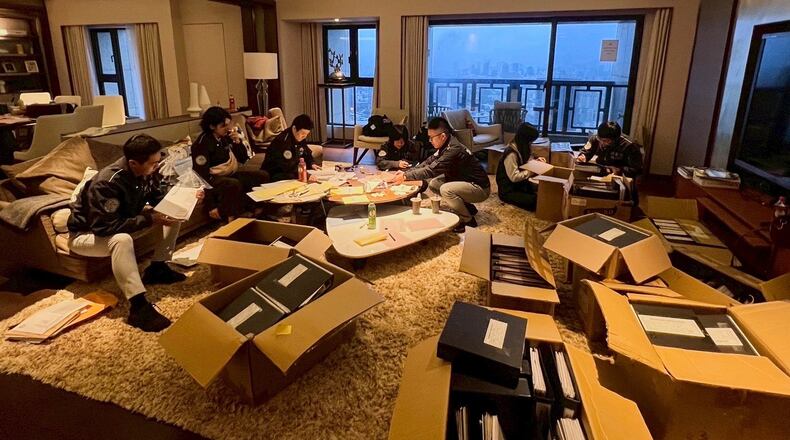 In this photo released by Ministry of Justice Investigation Bureau, Investigation Bureau agents check documents after they seized an apartment which belongs to the suspected head of a criminal scamming syndicate, in Taipei, Taiwan, Tuesday, Nov. 4, 2025. (Ministry of Justice Investigation Bureau via AP)