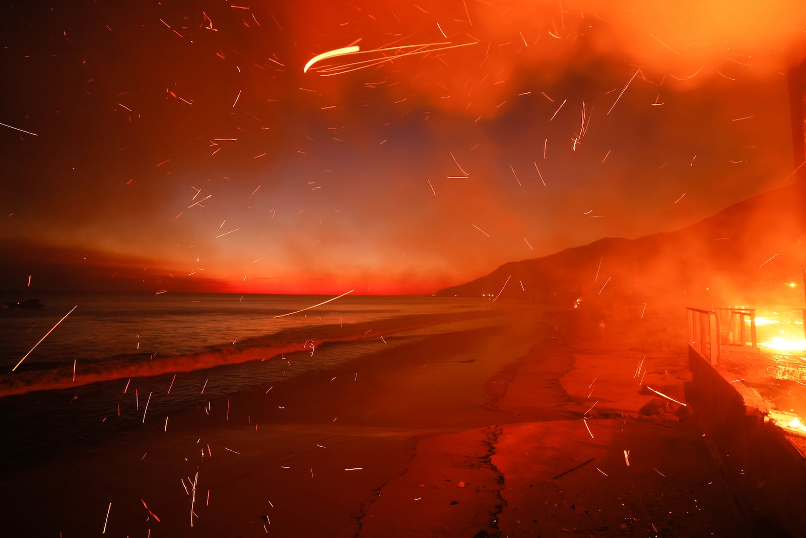 FILE - The Palisades Fire burns a beach front property Wednesday, Jan. 8, 2025 in Malibu, Calif. (AP Photo/Etienne Laurent, File)