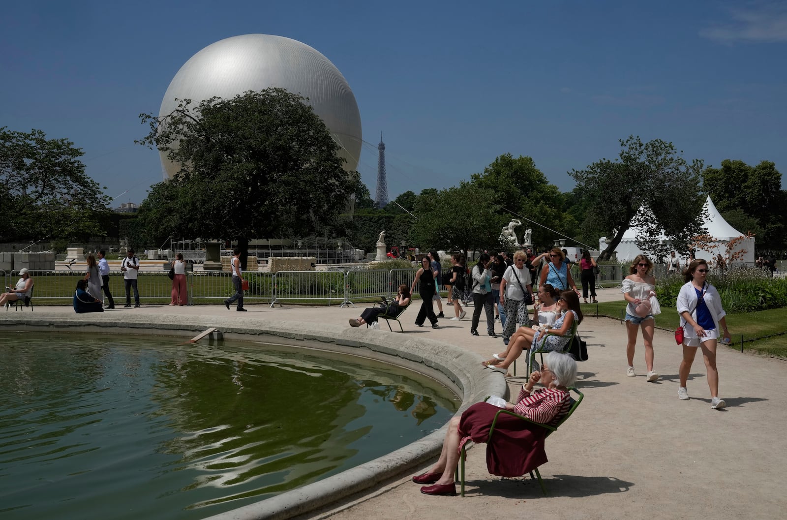 People walk past the Olympic cauldron at the Tuileries Gardens, ahead of its nightly summer relaunch starting June 21, in Paris, Thursday, June 12, 2025. (AP Photo/Michel Euler)