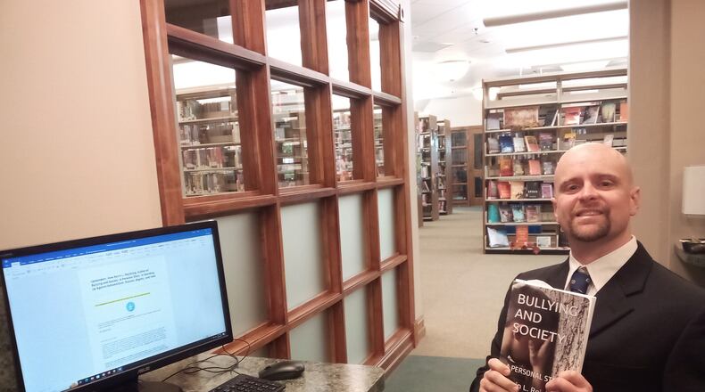 Reichling with a copy of his recently published book - an autobiographical story called "Bullying and Society," which explores the effects of chronic bullying on victims.