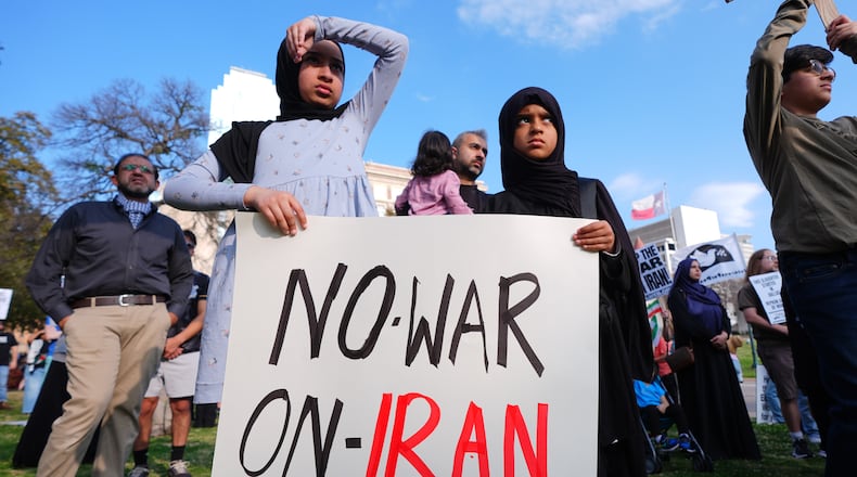 Children hold a sign protesting war against Iran during an antiwar demonstration at Dealey Plaza in downtown Dallas, Sunday, March 1, 2026. (AP Photo/LM Otero)
