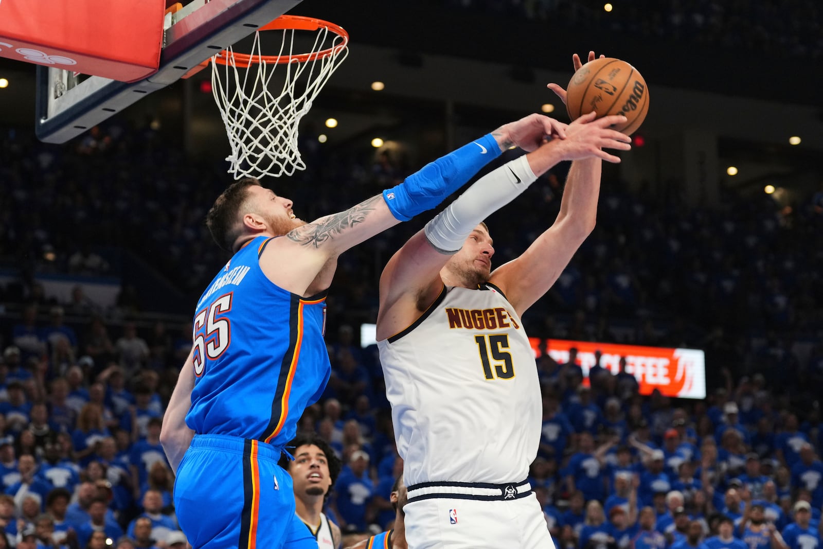 Oklahoma City Thunder's Isaiah Hartenstein (55) and Denver Nuggets' Nikola Jokic (15) compete for a rebound in the second half of Game 7 in the Western Conference semifinals of the NBA basketball playoffs, Sunday, May 18, 2025, in Oklahoma City. (AP Photo/Kyle Phillips)