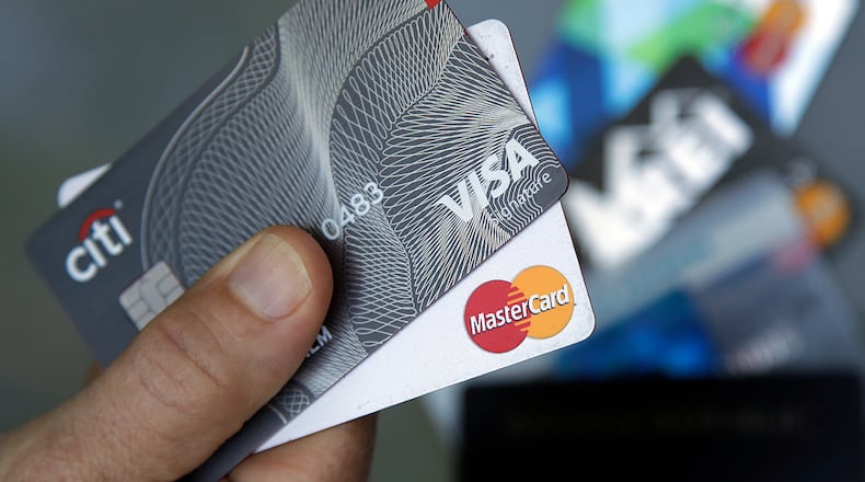 FILE- A consumer holds a Visa and Mastercard credit card (AP Photo/Elise Amendola, File)