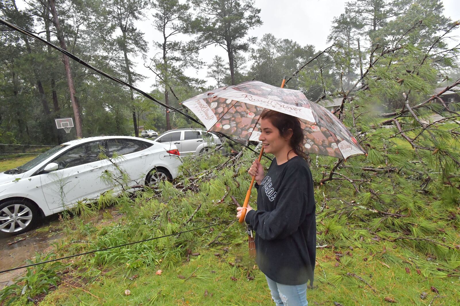 September 11, 2017 Columbus - Monica Ogle watches a fallen tree damaged her and her finance's cars at their home in west of Columbus on Monday, September 11, 2017. He had to move his car to a safe parking spot. The Georgia coast was hit hard Monday morning, with pounding rains, roaring winds and storm surge. More than 87,000 Georgia Power customers were without power in the Savannah area, as were another 96,000 from Brunswick and St. Simons south to St. Marys, at the Florida line. HYOSUB SHIN / HSHIN@AJC.COM