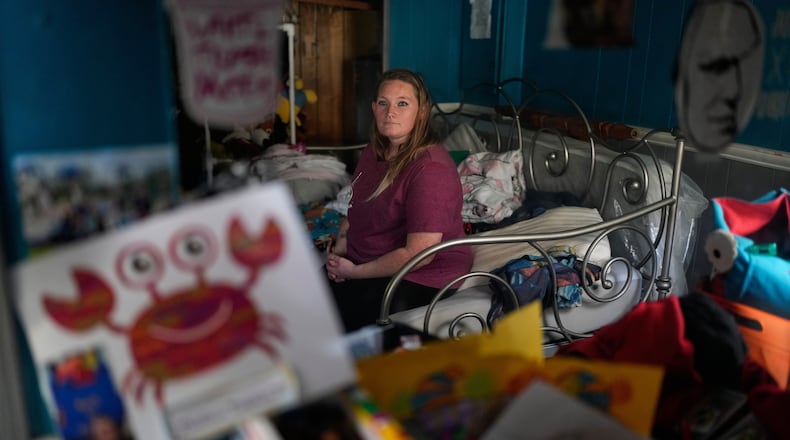 Dianna Tompkins looks at a mirror while she sits on a bed at her home in Demotte, Ind., Dec. 17, 2025. (AP Photo/Nam Y. Huh)