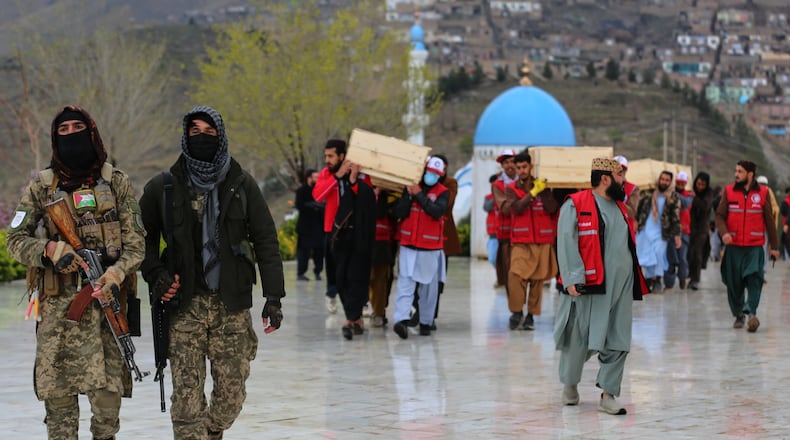 Taliban security personnel guard as people carry the remains of victims of a Monday airstrike on a drug rehabilitation hospital, ahead of the burials Wednesday, March 18, 2026, Kabul, Afghanistan. (AP Photo/Siddiqullah Alizai)
