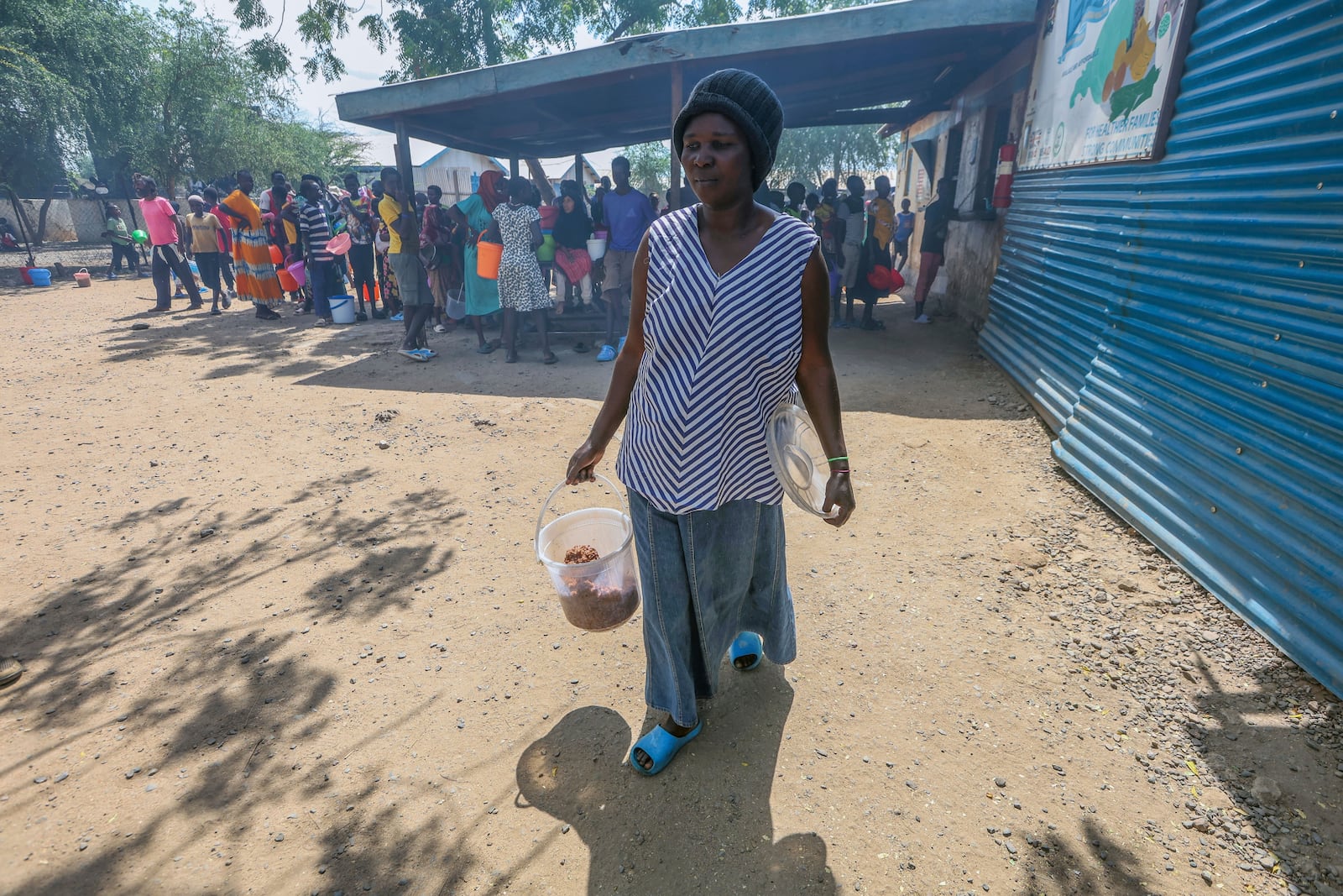 Aujene Cimanimpaye, from the Democratic Republic of Congo, brings lunch to her family at the Kakuma Refugee Camp in Turkana County, Kenya, Wednesday, June 4, 2025. (AP Photo/Andrew Kasuku)