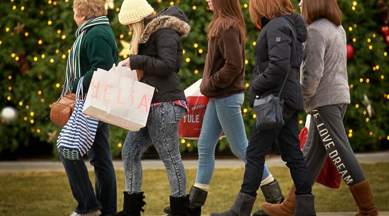 Black Friday shoppers walk past the large Christmas tree on the Greene Town Center in Beavercreek. JIM WITMER / STAFF