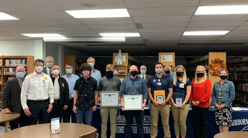 The Fairborn Board of Education, Fairborn Fire Chief Dave Reichert and Mayor Paul Keller present Coach Bronson Marlett, trainers Jaci Combs and TJ Tillman and students Bailey Snapp and Andrew Yeary with awards Oct. 1 for saving Bennet Hart's life. Hart is in the black with curly hair. CONTRIBUTED