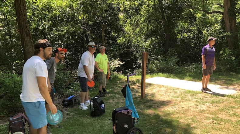 Sam Hartleroad, Garrett Heise, Brian Foster and J.P. Elam (from right) admire Russ Foster’s tee shot from the 3rd hole of the disc golf course at Armco Park in Warren County. STAFF/LAWRENCE BUDD