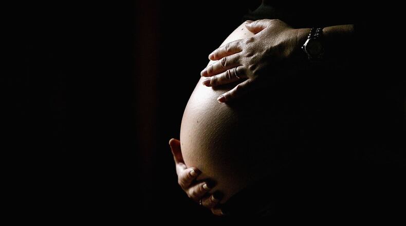 A pregnant woman holds her stomach. (Getty Images)