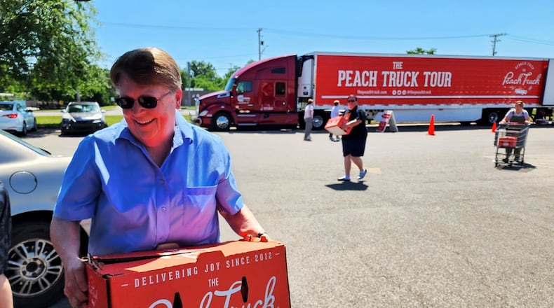 Nancy Greenslade purchases peaches from The Peach Truck at Rural King in Hamilton last year. PHOTO BY NICK GRAHAM/STAFF