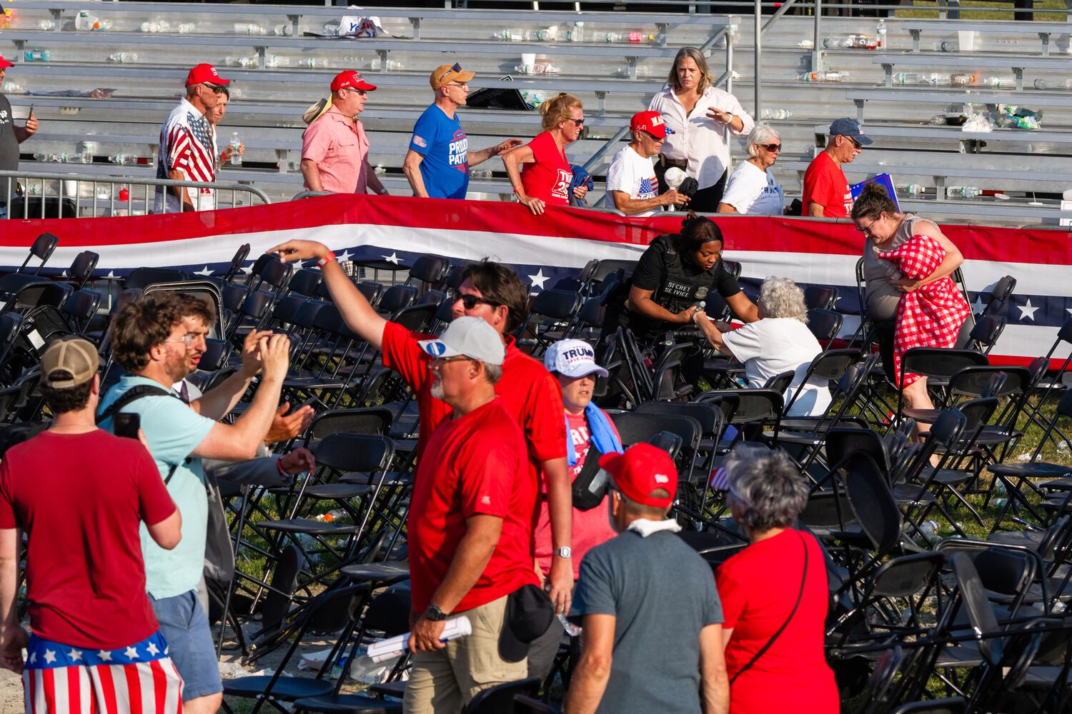 People in the aftermath of the assassination attempt on former President Donald Trump, including a Secret Service agent, right, helping an older person, in Butler, Pa., July 13, 2024.