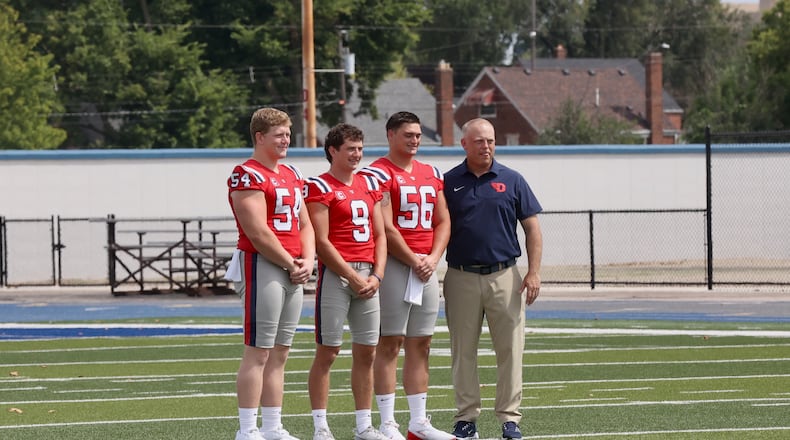 Dayton football coach Trevor Andrews, right, poses for a photo with team captains Ben Huefner (54), Cam Cope (9) and Ryan Iiams at Media Day on Sunday, Aug. 17, 2025, at Welcome Stadium. David Jablonski/Staff