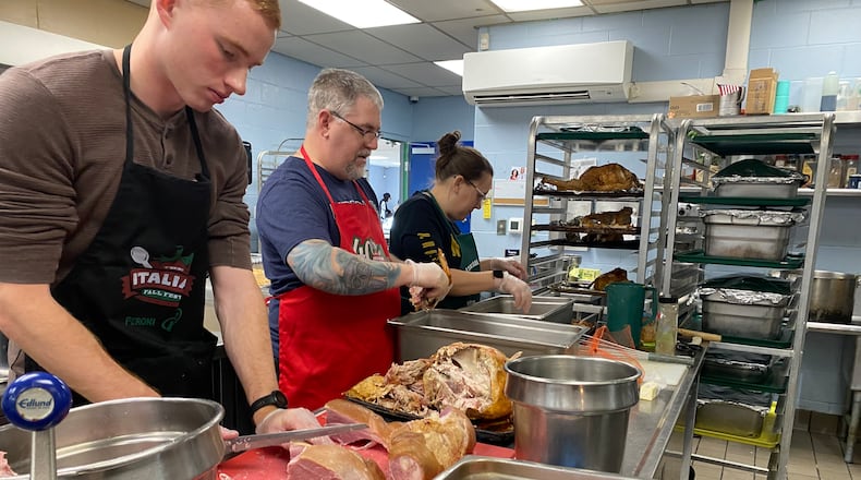 Harrison Michael, far left, Josh Elliot and Sara Elliot, all volunteers at House of Bread, cut up turkey and ham for people eating at  House of Bread on Thursday, Nov. 24, 2022. Eileen McClory / STAFF