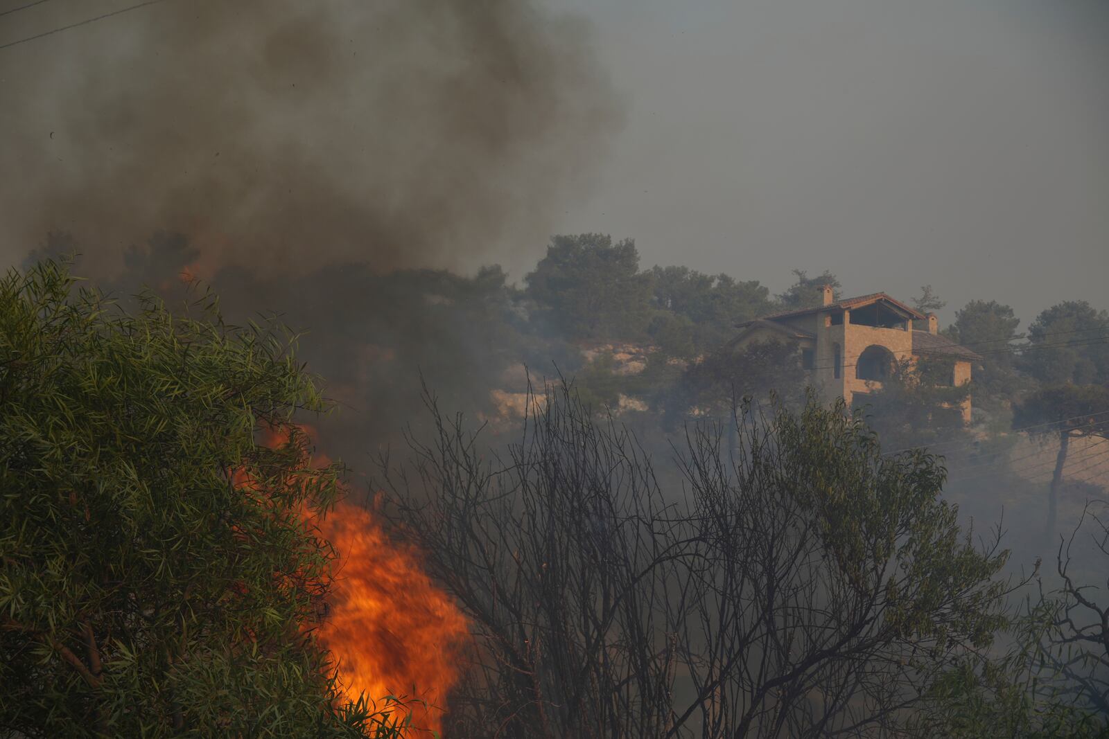Flames burn near a house in Souni village, Cyprus, during a massive wildfire on the southern side of the east Mediterranean island nation's Troodos mountain range, Thursday, July 24, 2025. (AP Photo/Petros Karadjias)
