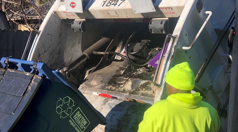 A sanitation worker picks up recycling on Wednesday in Dayton. CORNELIUS FROLIK / STAFF