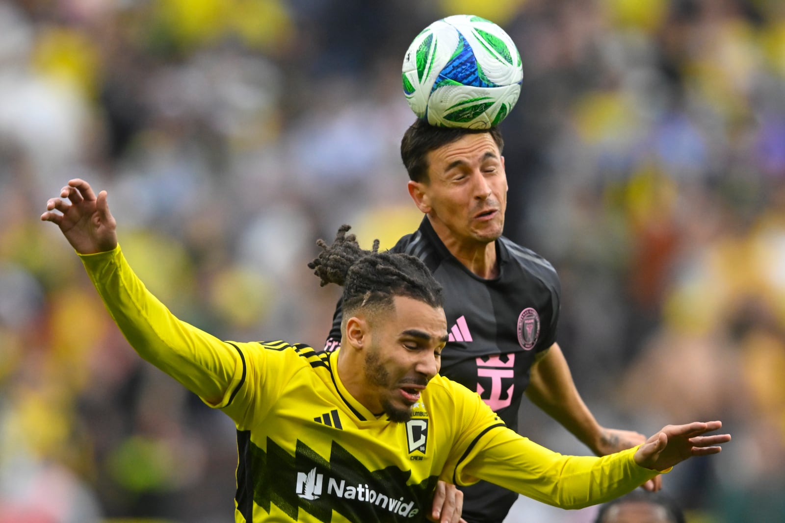 Inter Miami midfielder Tadeo Allende, top, heads the ball over Columbus Crew defender Mohamed Farsi, bottom, during the first half of an MLS soccer match Saturday, April 19, 2025, in Cleveland, Ohio. (AP Photo/David Richard)